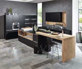 large long kitchen island with seating and prep area and kitchen sink behind, ovens to left