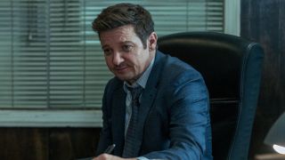 Jeremy Renner as Mike in Episode 2 of Mayor of Kingstown Season 3 writing on a notepad while sitting at his desk.