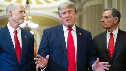 US President Donald Trump (C), alongside Senator Rick Scott (L), Republican from Florida, and Senator John Barrasso (R), Republican from Wyoming, speaks to the press after a lunch meeting with Senate Republicans at the US Capitol in Washington, DC, on June 24, 2026. President Trump said Wednesday he will refuse to sign a landmark housing bill, passed by Congress with broad bipartisan support, until lawmakers approve legislation that would overhaul American elections and restrict voter registration. (Photo by SAUL LOEB / AFP via Getty Images)