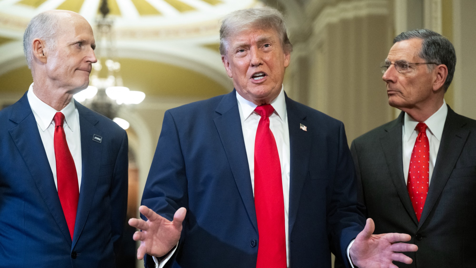 US President Donald Trump (C), alongside Senator Rick Scott (L), Republican from Florida, and Senator John Barrasso (R), Republican from Wyoming, speaks to the press after a lunch meeting with Senate Republicans at the US Capitol in Washington, DC, on June 24, 2026. President Trump said Wednesday he will refuse to sign a landmark housing bill, passed by Congress with broad bipartisan support, until lawmakers approve legislation that would overhaul American elections and restrict voter registration. (Photo by SAUL LOEB / AFP via Getty Images)