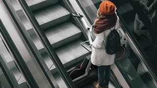 Concept art of woman with BMW Clever Commute e-scooter on an escalator