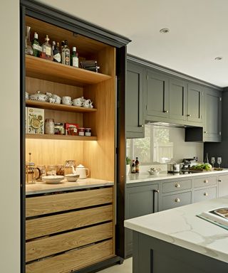 A Shaker kitchen in forest green with a built-in pantry