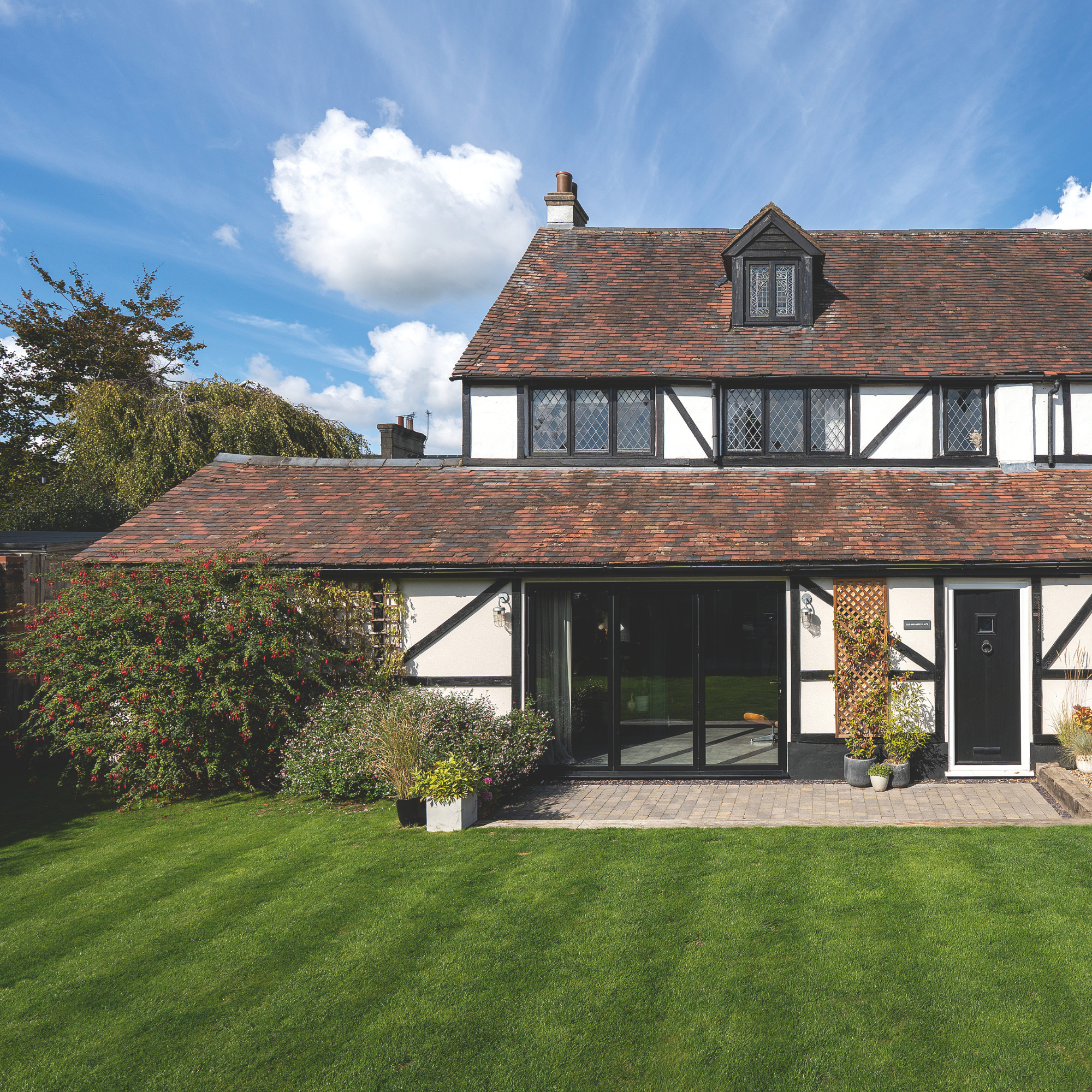 Lush green lawn at the front of a tudor-style detached home.