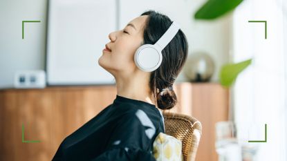 Woman sitting back in chair with eyes closed, listening to the best podcasts for anxiety through headphones