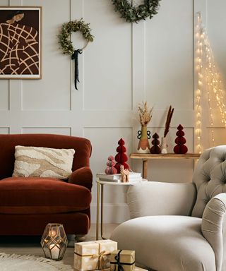 living room decorated with festive ornaments with wall-mounted wreaths, paper Christmas trees and fair lights