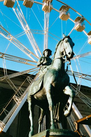 A statue in front of a ferris wheel taken on Harman Phoenix 200 35mm film