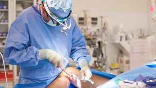 Doctor operating on leg in operating room