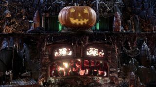 A jack-o-lantern stands atop a roaring fireplace in a dingy underground lair in the Mad God Ghoul Log