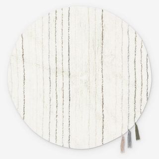 A round, neutral rug with tassels