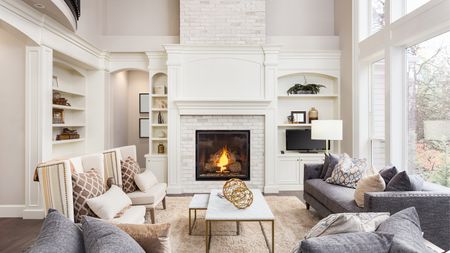 Beautiful living room interior with tall vaulted ceiling, loft area, hardwood floors and fireplace in new luxury home