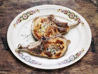 Two cooked pork loin chops on a plate with floral motif