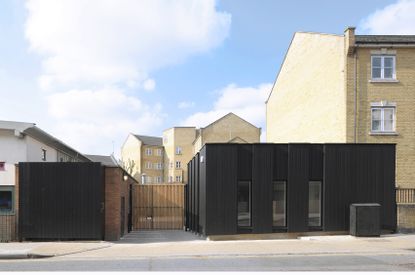 Two single level cube-shape buildings either side of a gate that leads to an estate behind. 