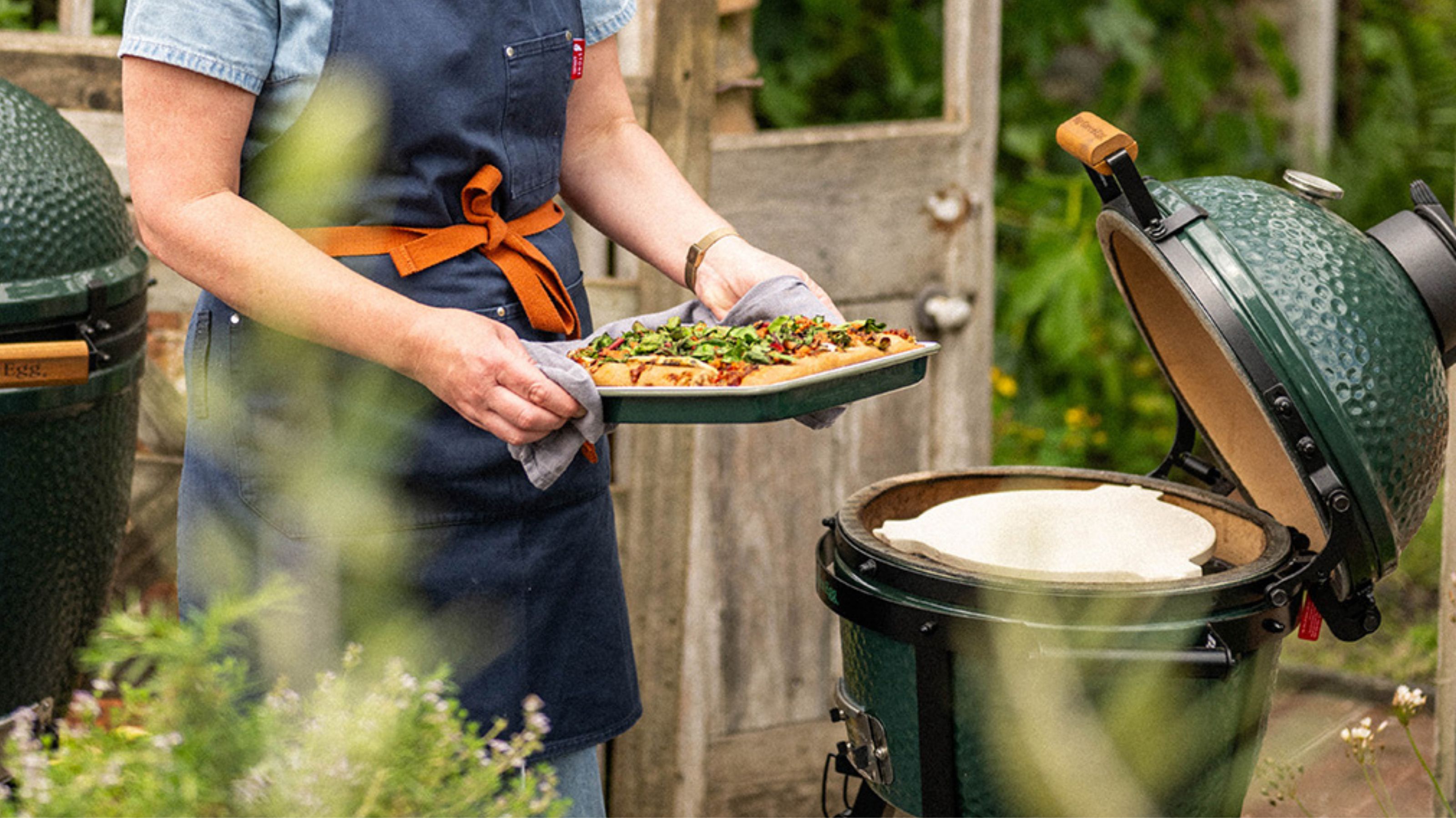 big green egg in garden with baking tray with focaccia being places on it