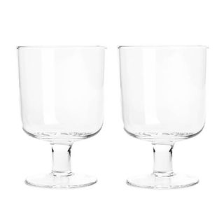 Two clear short stemmed square wine glasses.
