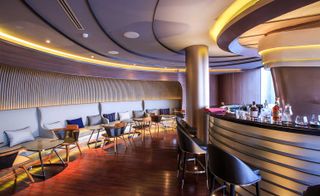 Curved bar featuring hardwood flooring and leather and wood seating