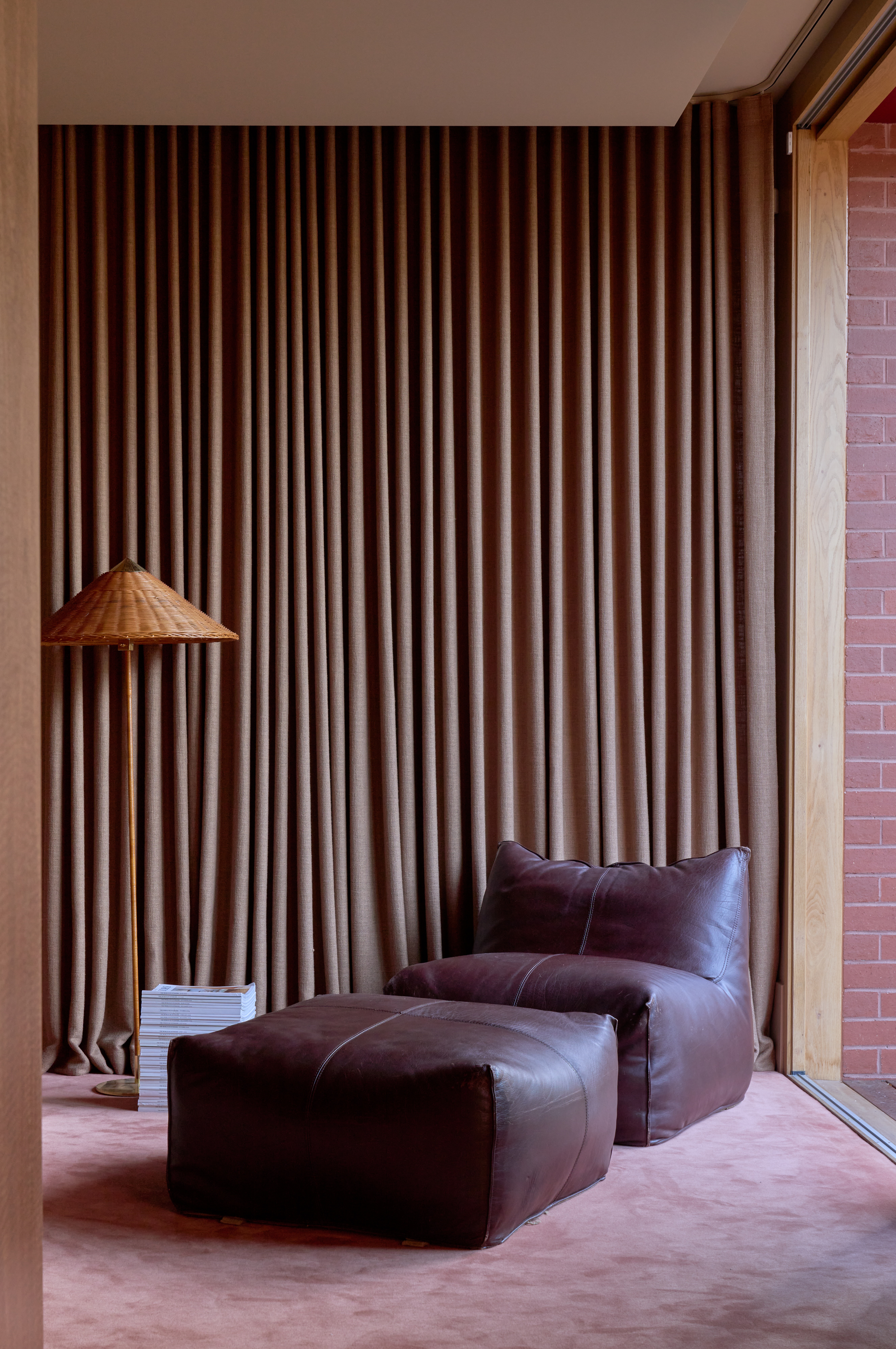 A contemporary reading corner in a soft contrast palette of pink, clay, umber, linen, and leather colors and materials