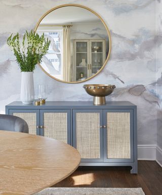 Dining room with cloud wallpaper, large round mirror, sideboard, table