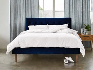 A navy blue velvet bed with white bedding