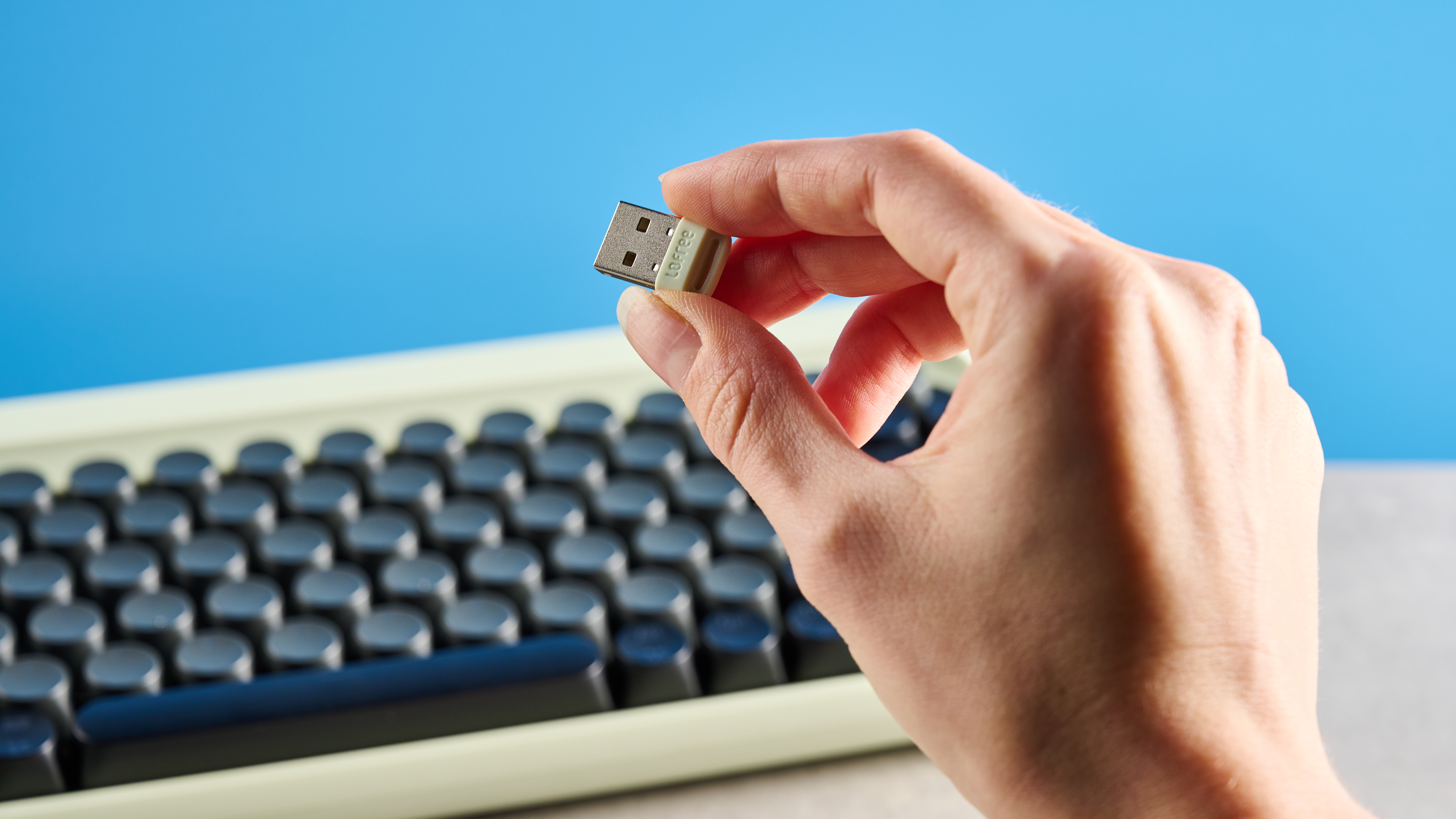 The Lofree DOT on a stone surface with its 2.4G receiver in hand in the foreground