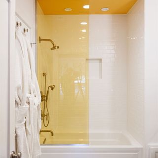 bathroom with gold fixtures and white and yellow tiles