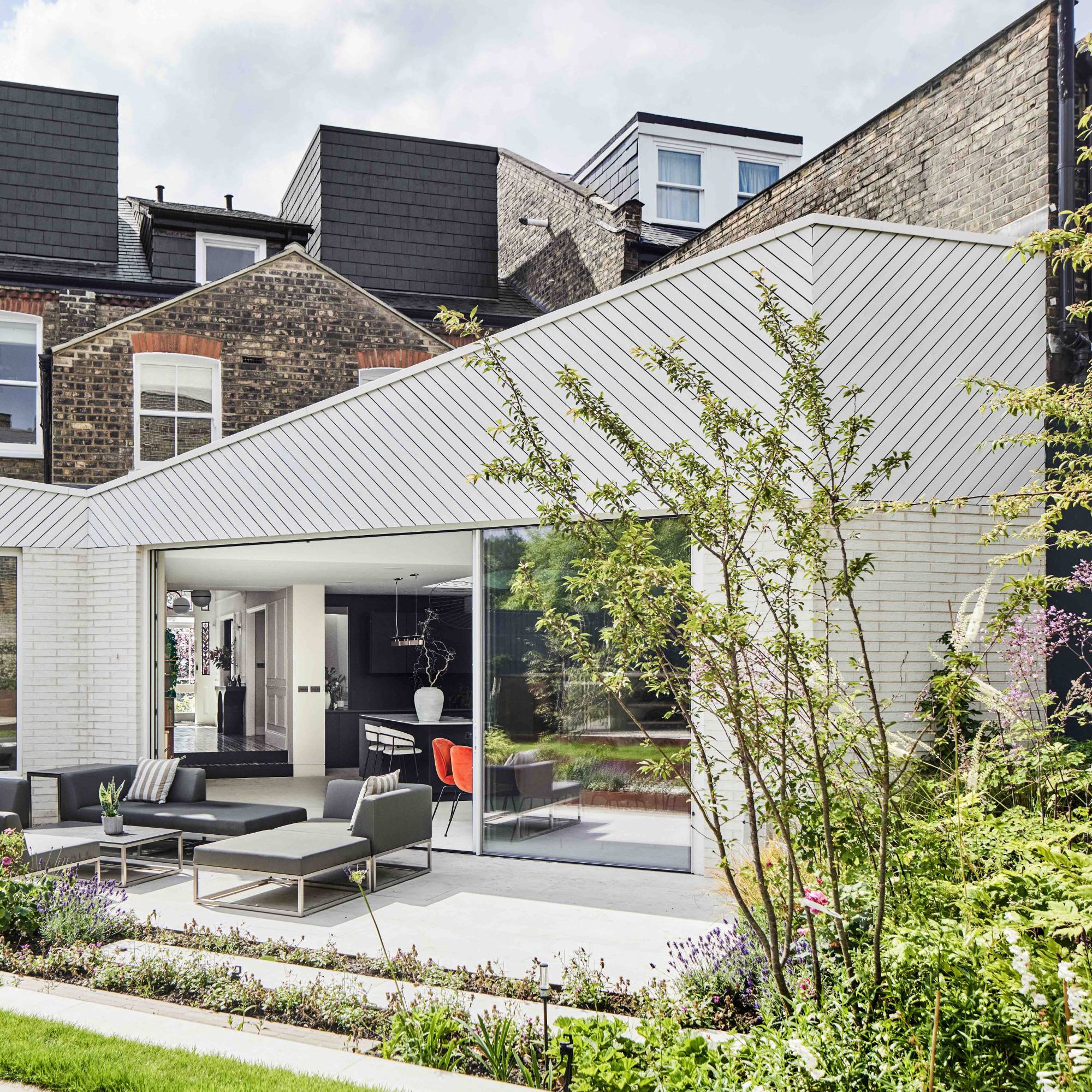 extension to terrace house clad in white brick and timber with patio