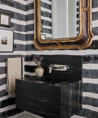 powder room with black and white horizontal striped walls and black marble basin