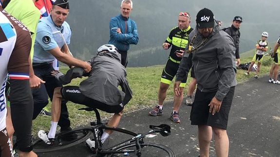 A French gendarme helps Chris Froome get up after pulling him off the road