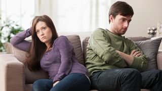 A man and a woman face away from each other on couch