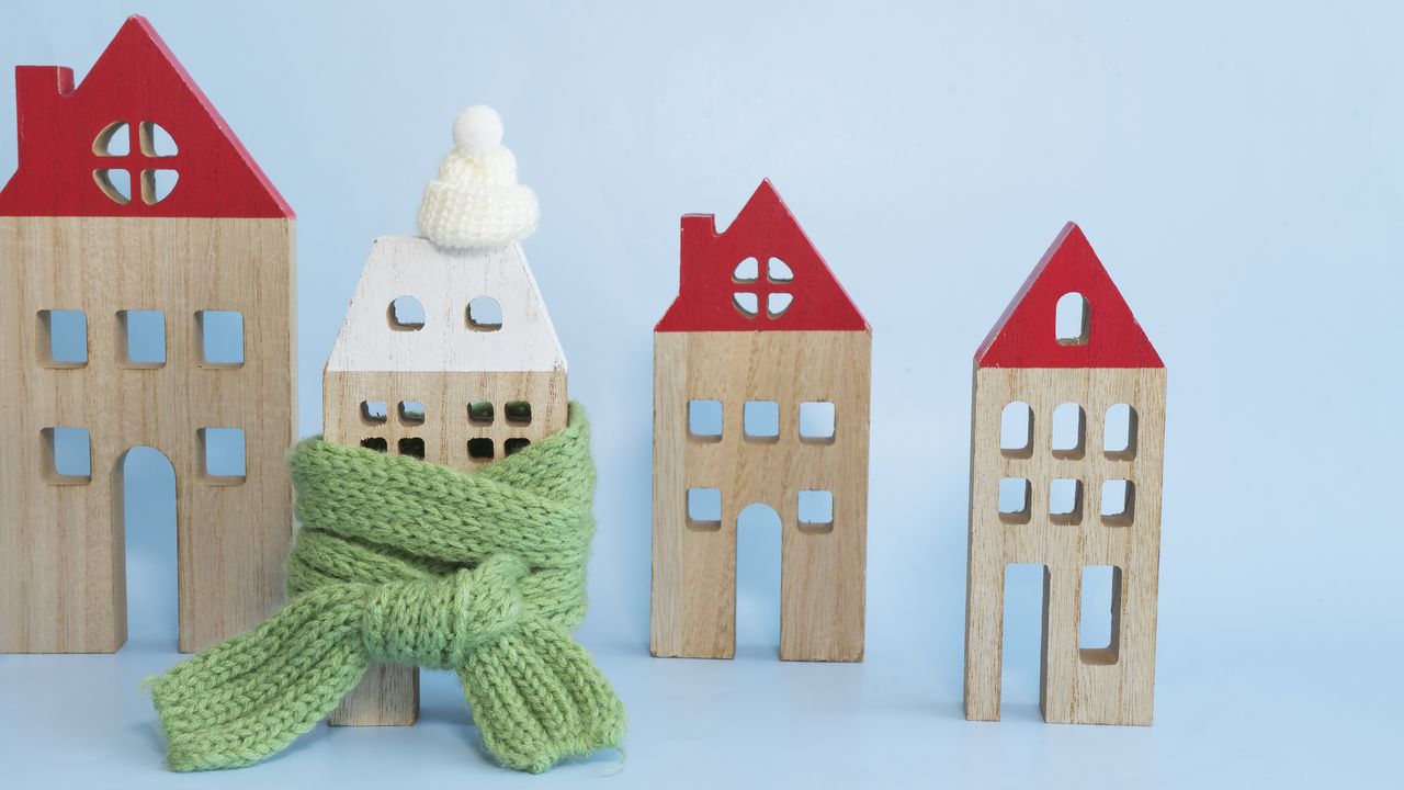 A figurine of a house wrapped in a green scarf next to other houses