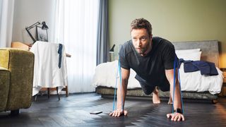 Man uses the Straffr smart fitness band to workout in a bedroom