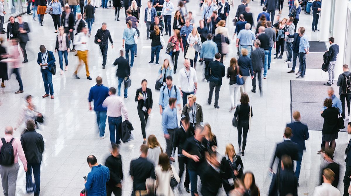 A crowd of people walking in a large building. 