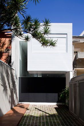 A driveway leading to a gate and a white upper level building.