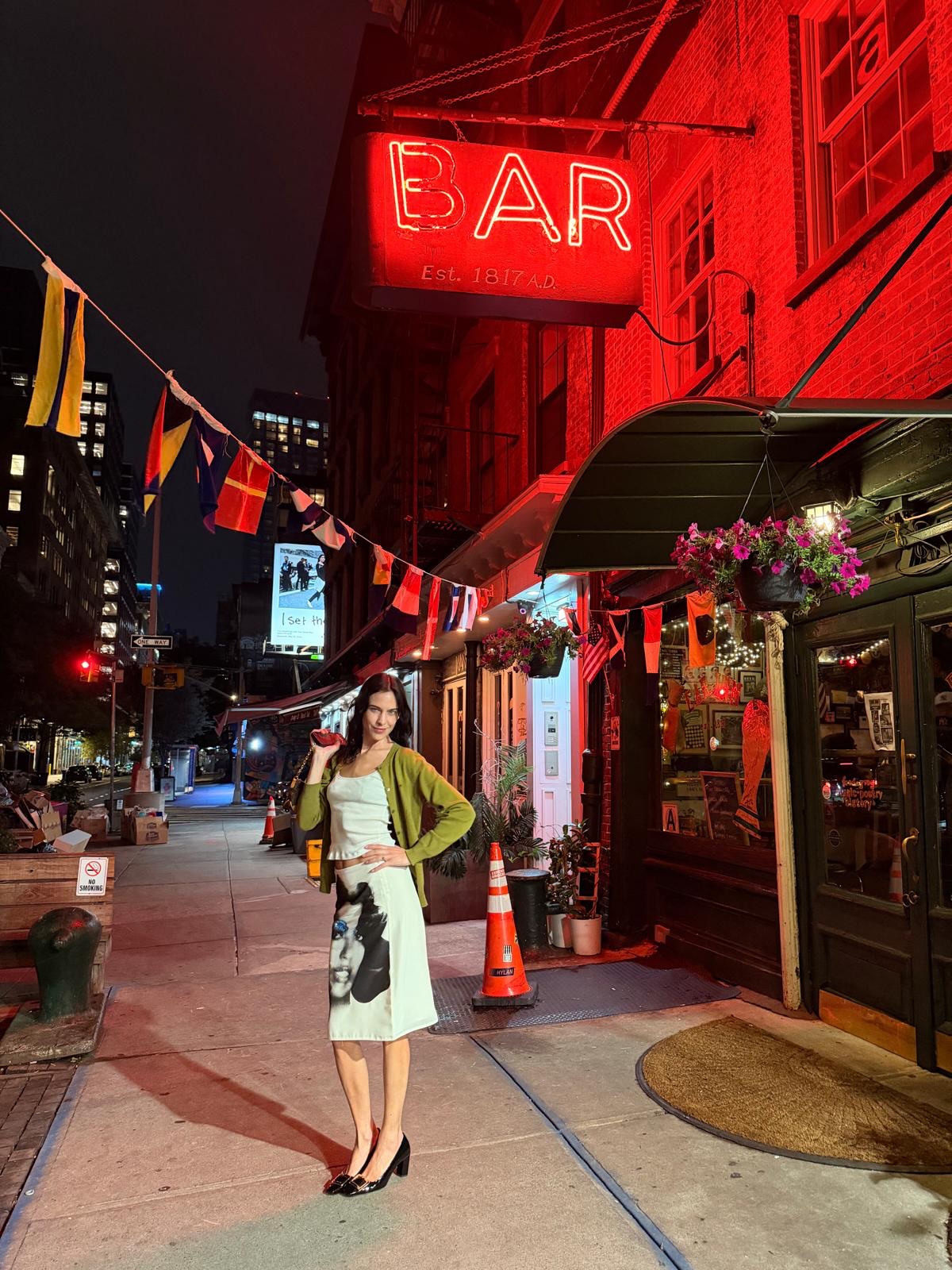 An image of @alexachung wearing Versace's face skirt with a green cardigan whilst in New York.