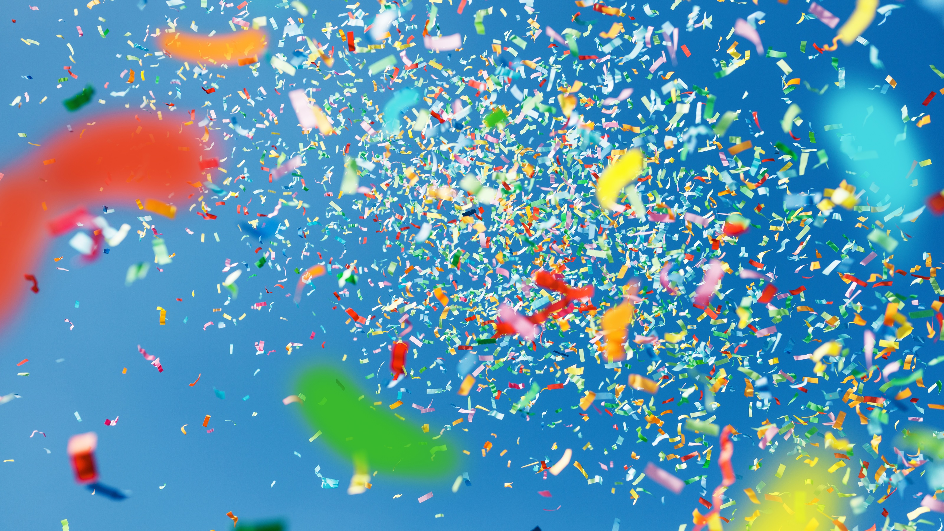 Confetti thrown in the air against a blue sky.