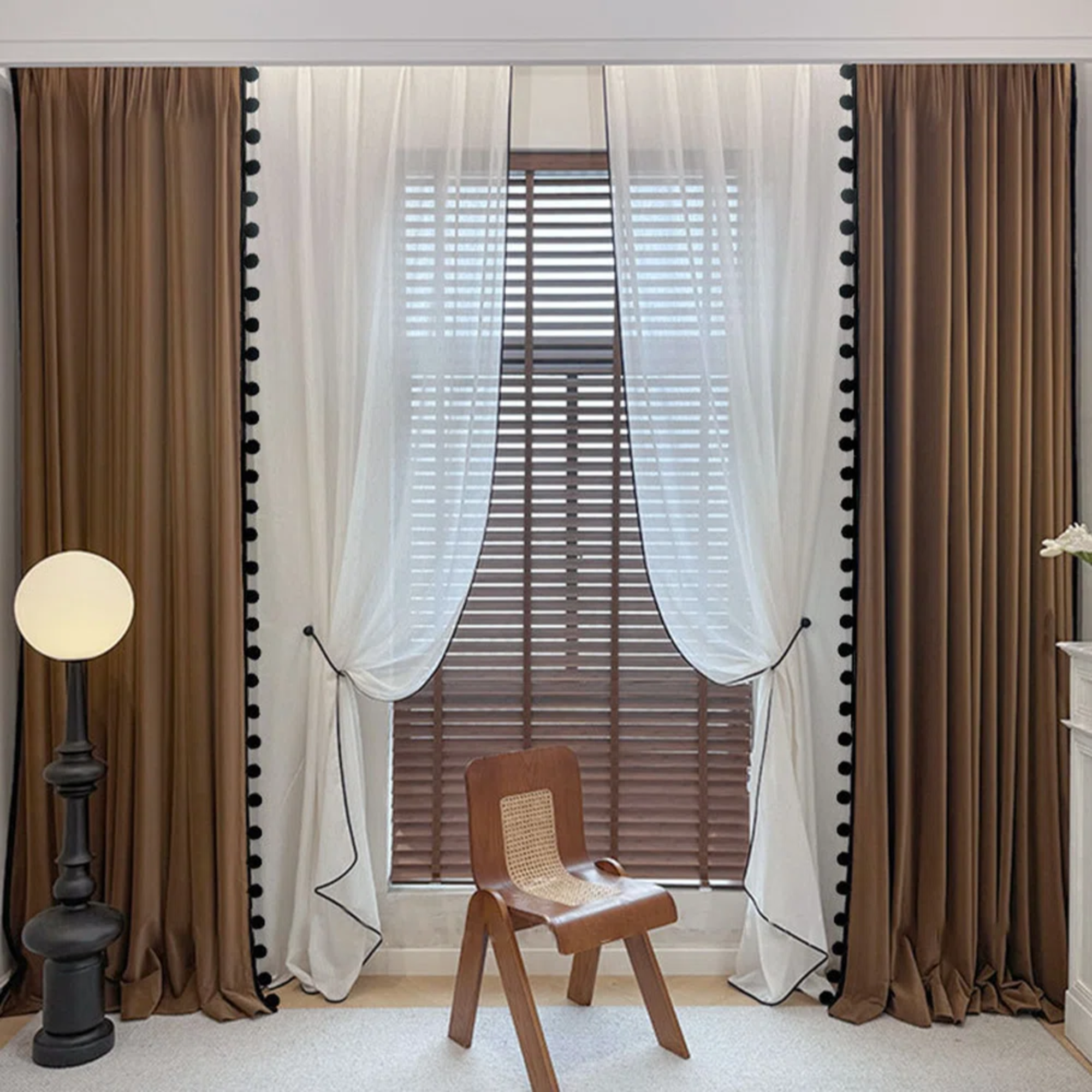 a room with brown drapes with pompoms on the sides and white drapes behind them
