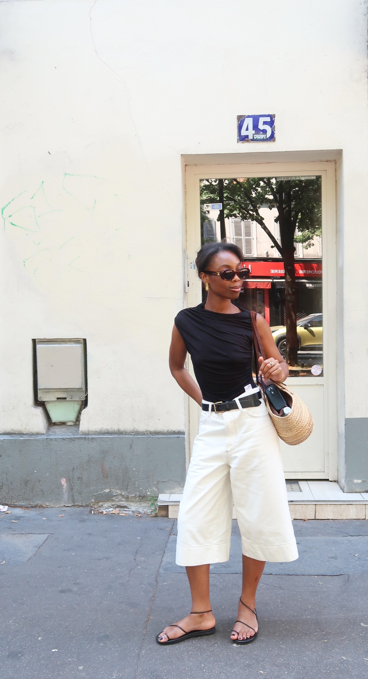Avalon Afriyie wears denim PAIGE jorts, a black Ninety Percent top and Ancient Greek Sandals