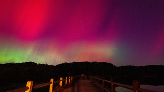 Green and pink lights over a brown wooden bridge