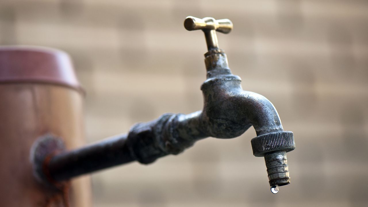 Running out of water image of old faucet with water leaking drop