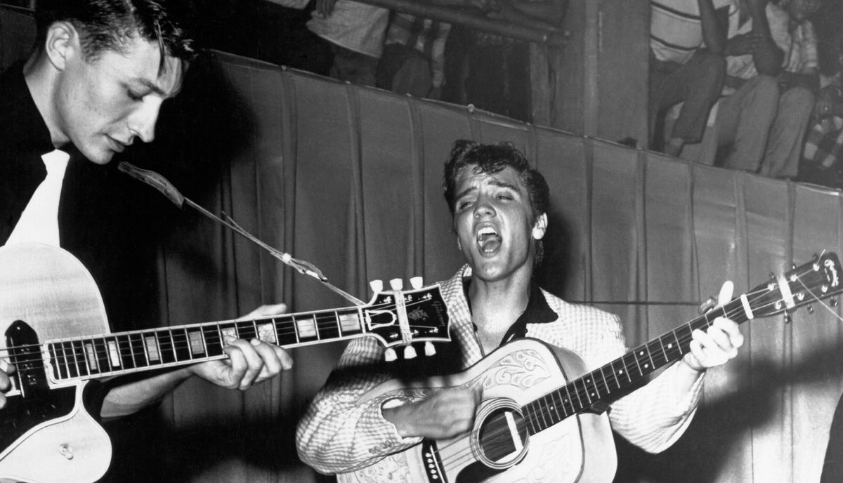 Scotty Moore (left) and Elvis Presley perform onstage at Fort Homer Hesterly Armory in Tampa, Florida on July 31, 1955