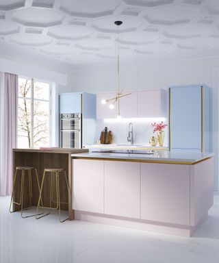 An example of modern kitchen lighting ideas showing a kitchen in shades of pastel pink and blue with gold edging
