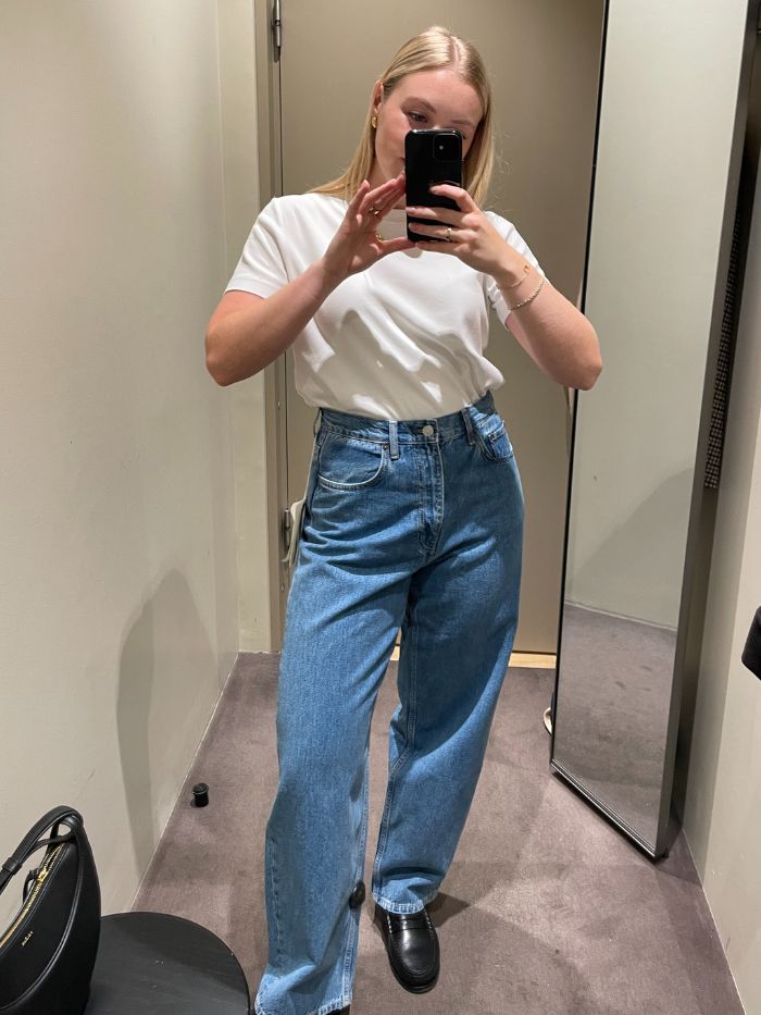Woman wears white T-shirt, blue jeans and black loafers