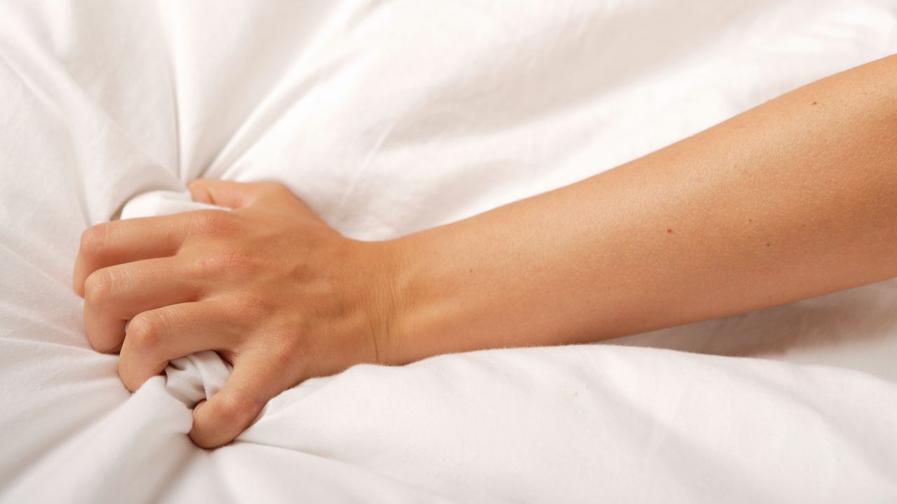 woman&#039;s hand gripping bedsheet