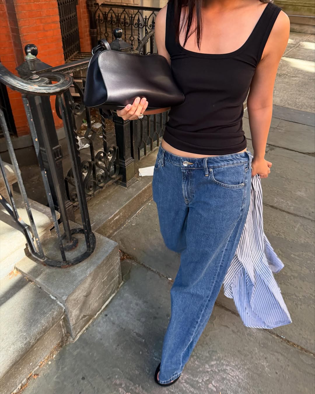 Woman wearing long, baggy jeans fall denim trend 2025.