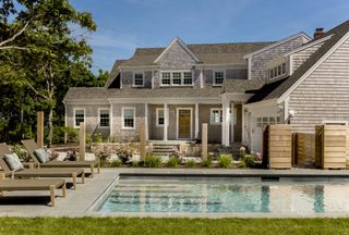 cape cod house exterior with swimming pool, garden, and sun loungers