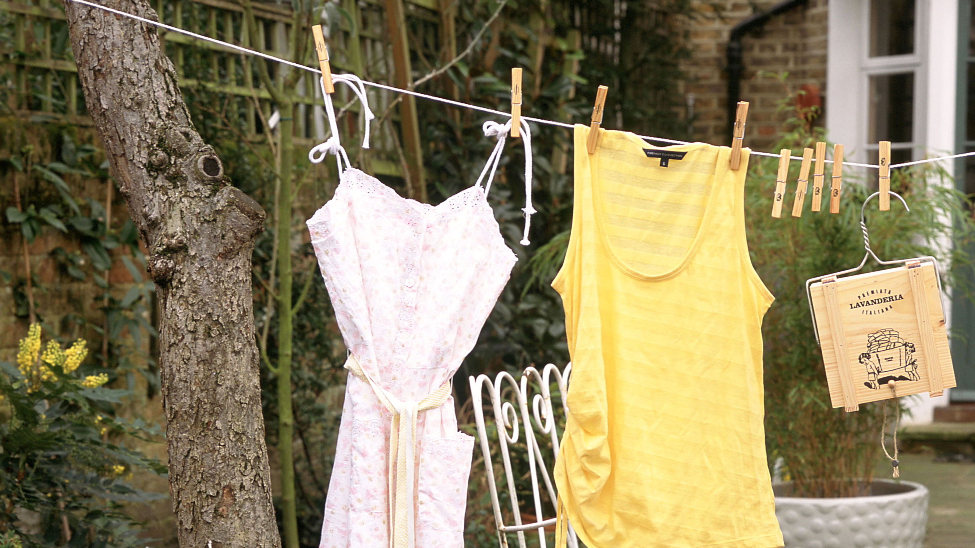 Washing line with white dress and yellow top with wooden pegs