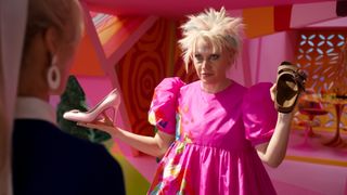 Kate McKinnon as Barbie, holding a heel and a Birkenstock in the Barbie movie