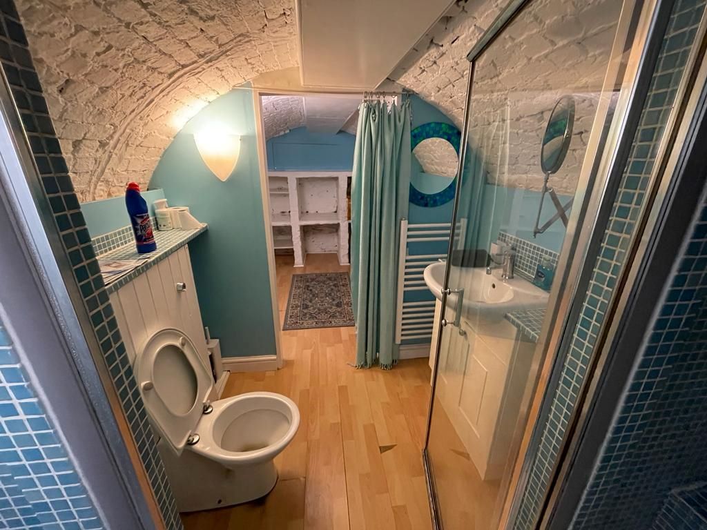 The bathroom with blue tiles and separate shower before being ripped out