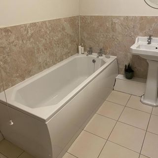 dated neutral bathroom with bath and tiled walls