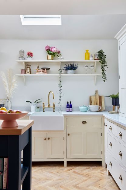 A white shaker kitchen with two white open shelves featuring plants, and various stylish kitchen accessories and utensils
