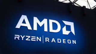 The AMD Logo with the Ryzen and Radeon brand logos underneath on a spotlit wall